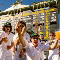 Fans dressed in white cheering on their cricket team in front of the Heritage Scoreboard at Adelaide Oval 