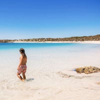 a young child standing in the shallows of clear waters