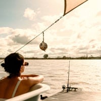 Someone leans on the edge of the bath overlooking the Murray River, as the fishing rod hangs in the water 
