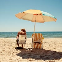a man sits under a beach umbrella on a deck chair on a sunny day on the beach